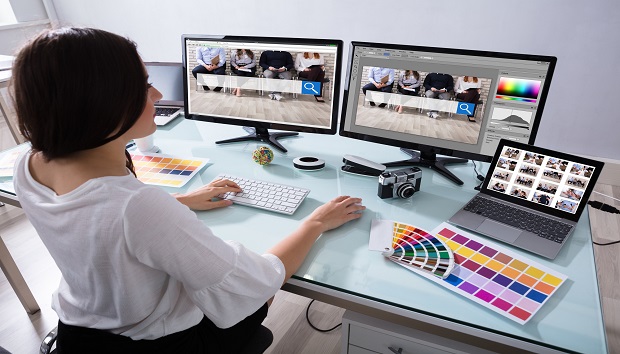 Close-up Of A Female Designer Working On Multiple Computer At Workplace